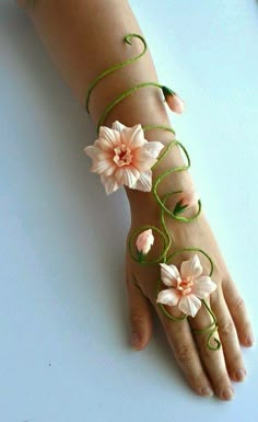 a woman's hand with flowers on it and green string attached to the wrist