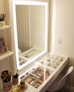 a white desk topped with a large mirror and lots of drawers under it's lights