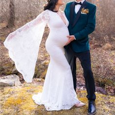 a pregnant woman in a white dress and a man in a blue suit pose for a photo