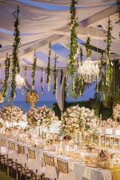 an outdoor wedding setup with chandeliers and flowers