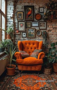 an orange chair sitting in front of a brick wall with pictures on the wall above it