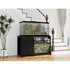 a fish tank sitting on top of a wooden cabinet next to a stair case with plants