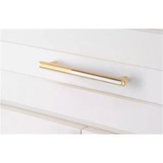 an image of a gold handle on a white cabinet door with drawers in the background