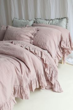 a pink bed with ruffled sheets and pillows