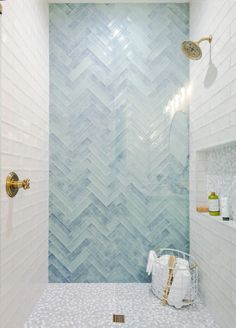 a bathroom with white and blue tiles on the wall, shower head, and tub