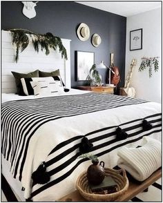 a bed with black and white striped bedspread in a bedroom next to plants