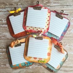 four blank notepads are sitting on a wooden table with clipboards attached to them