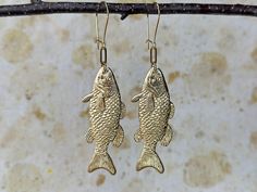 These big gold brass fish earrings are a fun way to make a bold summer statement. Wear them on a yacht or fishing from a dingy, they make the perfect gift for an outdoorsy wife or girlfriend who isn't afraid to bait her own hook and reel in the biggest catch of the day. Dimensions & Materials 3.5 inches high x 1 inch wide charms are raw brass with gold plated ear wires My latest nature inspired jewelry line includes dainty minimalist geometric shapes with natural stones. All brass is polished to a soft brushed shine and is sealed with a natural wax coating to slow down the tarnishing process that is common with brass and silver jewelry. Jewelry is handmade in my 100% wind powered home studio located in Hudson, New York. All orders are shipped ready for gifting in a hand printed envelope an Gold Fish-shaped Earrings With Fish Hook, Fish Earrings, Catch Of The Day, Jewelry Nature, Fisherman Gifts, Earrings Summer, Gold Fish, Paper Jewelry, Nature Inspired Jewelry