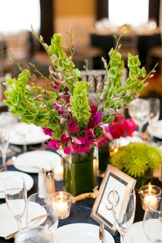 the centerpieces on this table are filled with flowers and greenery, along with candles