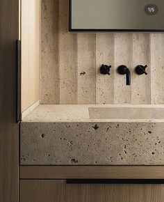 a bathroom sink with two faucets and a mirror above it in a wood paneled room