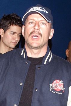 a man in a blue jacket and hat standing next to other men