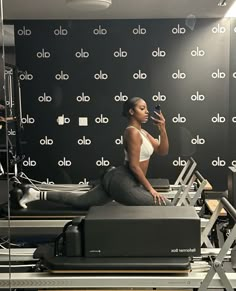 a woman sitting on top of a machine in front of a wall with alot