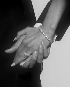 two people holding hands while wearing bracelets on their wrists and one person in a suit holds the other's hand