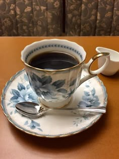 a cup of coffee on a saucer next to a spoon