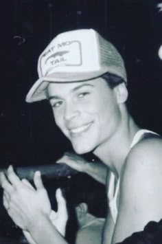 a black and white photo of a young man wearing a hat with his hands in the air