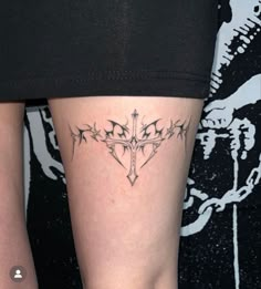 a woman's leg with a cross tattoo on her left thigh and an arrow in the middle