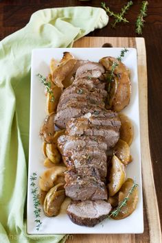 a white plate topped with meat covered in gravy next to potatoes and mushrooms