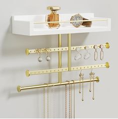 a white shelf with gold jewelry and watch hanging on it