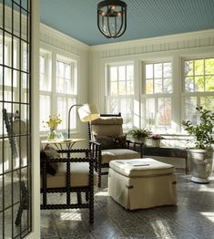 a living room filled with lots of furniture next to large windows and potted plants