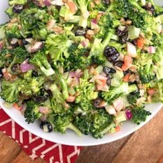 a white bowl filled with broccoli and other vegetables on top of a wooden table