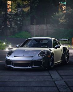 a silver sports car driving down a street at night