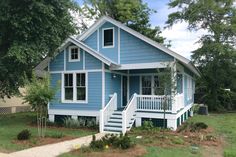 a blue house with white stairs and trees