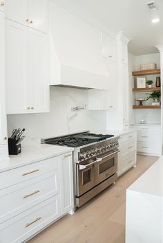 a kitchen with white cabinets and stainless steel stove top oven in the center of the room