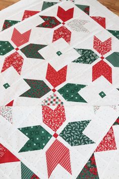 a quilted table topper with red, green and white christmas trees on it