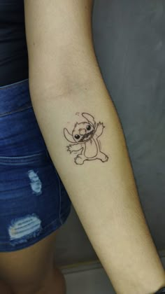 a woman's arm with a small tattoo of a dog on the left forearm