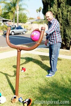 a man standing next to a pink ball on top of a metal pole in the grass