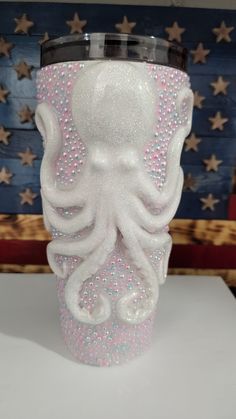 a white cup with an octopus on the side and stars in the background, sitting on top of a table