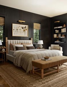 a bedroom with black walls and white bedding has a bench in front of the bed