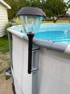 a light on the side of a pool next to a fenced in swimming pool