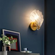 a light that is on the side of a blue wall next to a potted plant