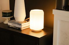 a white vase sitting on top of a table next to a lamp and bookend