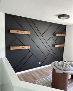 an empty room with black walls and wooden shelves on the wall, in front of a white