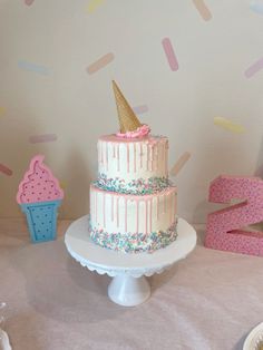 a birthday cake with sprinkles and an ice cream cone is on a table