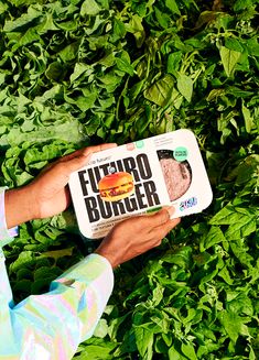 a man holding a carton of futurao burger on top of green leaves