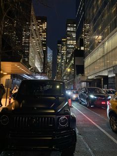 several cars are parked on the street in front of some tall buildings at night time