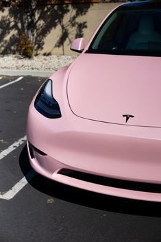 a pink tesla parked in a parking lot