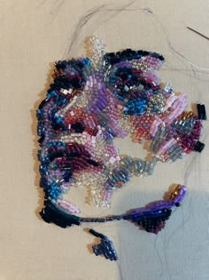 a piece of art that is made out of beads and other things on a white surface