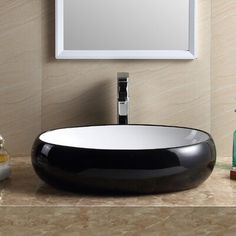 a black and white bowl sink sitting on top of a counter next to a mirror