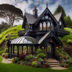 a black house with lots of windows and plants on the front lawn, surrounded by lush green grass