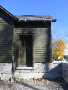 a house with a green door and window on the side of it's building