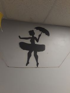 the silhouette of a woman holding an umbrella is painted on the wall above her head