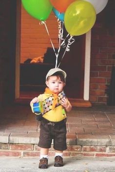 a little boy holding some balloons in his hands