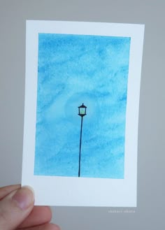 a hand holding up a piece of paper with a drawing of a street light on it