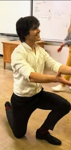 a woman sitting on the floor with her legs crossed and one hand extended in front of her face