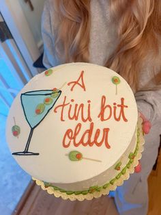 a woman holding up a cake that says, a fun bit older on it's side