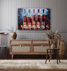 three bottles of liquor are sitting on a table in front of a vase and chair